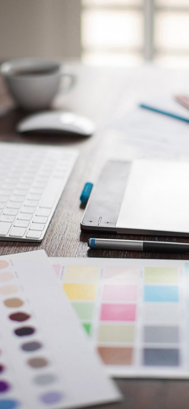 Computer, pen tablet, color swatches and sketches on a designer's workspace with a very shallow depth of field